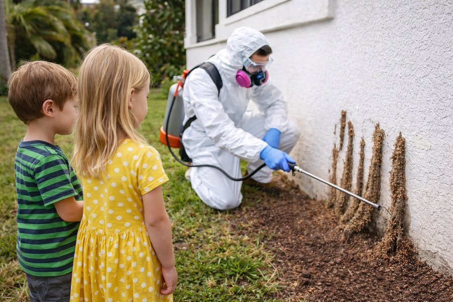 Is fumigation safe for pets risks - Pest control worker treating termites near children outside house.