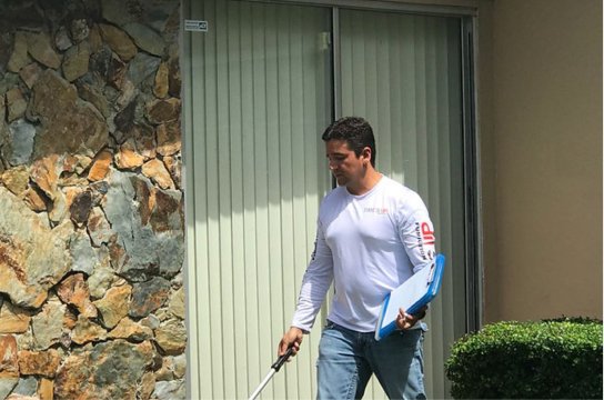 Termite Treatment & Pest Control​ Premium Tools - Pest control technician carrying equipment outside building