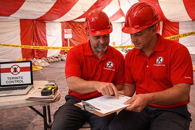About Us Communicate - Termite control supervisors reviewing paperwork inside tent.