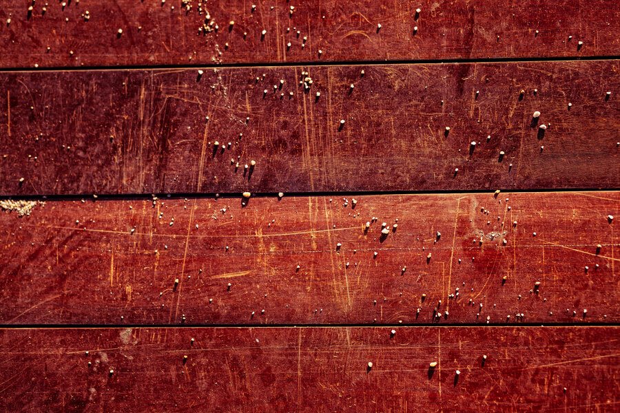 Red wooden surface with small white pellet-like droppings scattered across it.