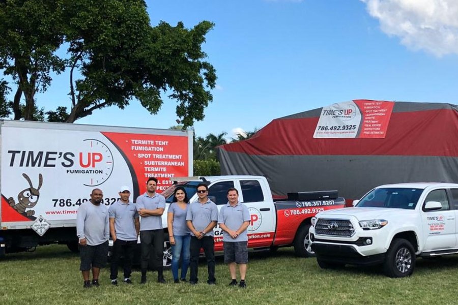 Where can I book a professional rodent removal service - Pest control team standing with branded service vehicles.