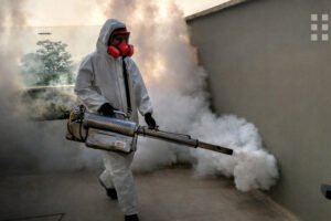 Who provides termite treatment services in my area - Pest control worker spraying outdoors with protective gear.