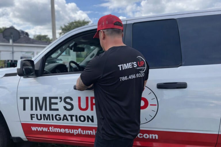 Tentless termite treatment - Technician standing next to branded pest control truck.